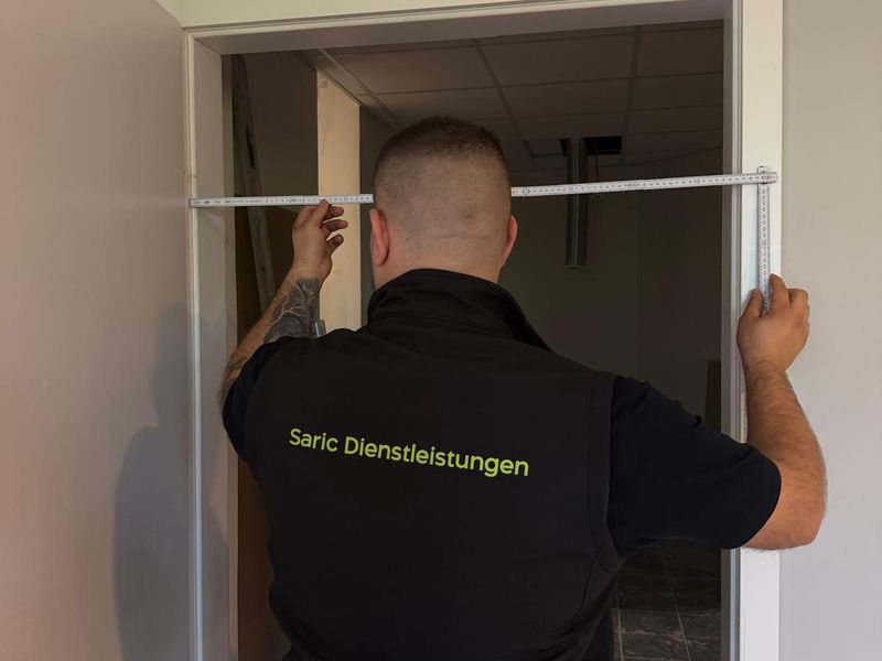 Saric-Mitarbeiter nimmt Maß an einer Tür im Objekt auf